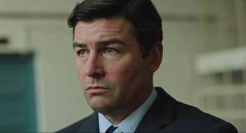Movie still from “Zero Dark Thirty” (2012), directed by Kathryn Bigelow – A person wearing a suit and tie; Close Up shot, Over the shoulder angle