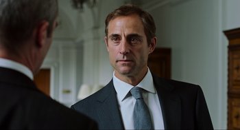 Movie still from “Zero Dark Thirty” (2012), directed by Kathryn Bigelow – A person wearing a suit and tie; Close Up shot, Over the shoulder angle