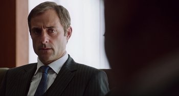 Movie still from “Zero Dark Thirty” (2012), directed by Kathryn Bigelow – A person wearing a suit and tie; Close Up shot, Over the shoulder angle