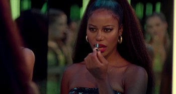 A beautiful young woman putting lipstick on in front of a mirror