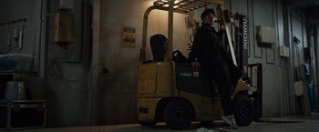 Movie still from “Zom 100: Bucket List of the Dead” (2023), directed by Yûsuke Ishida – A man standing in front of a yellow forklift; Wide shot, Low angle