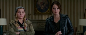 Movie still from “Zombieland: Double Tap” (2019), directed by Ruben Fleischer – Two women sitting in front of a painting in a living room; Medium shot, Over the shoulder angle
