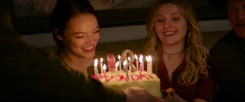 Movie still from “Zombieland: Double Tap” (2019), directed by Ruben Fleischer – Two women smile as they light candles on a birthday cake; Close Up shot, Over the shoulder angle