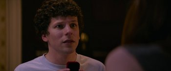 Movie still from “Zombieland: Double Tap” (2019), directed by Ruben Fleischer – A man with curly hair is holding a cell phone; Close Up shot, Over the shoulder angle