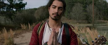 Movie still from “Zombieland: Double Tap” (2019), directed by Ruben Fleischer – A man with long black hair is praying; Close Up shot, Over the shoulder angle