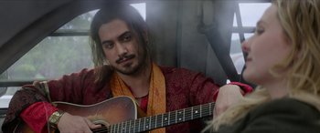 Movie still from “Zombieland: Double Tap” (2019), directed by Ruben Fleischer – A man with long hair playing an acoustic guitar; Close Up shot, Over the shoulder angle