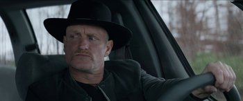 Movie still from “Zombieland: Double Tap” (2019), directed by Ruben Fleischer – A man in a hat sitting in the driver's seat of a car; Close Up shot, Over the shoulder angle