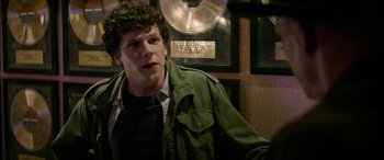 Movie still from “Zombieland: Double Tap” (2019), directed by Ruben Fleischer – A man in a green jacket standing in front of a gold record; Close Up shot, Over the shoulder angle