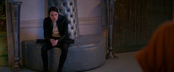 Movie still from “Zombieland: Double Tap” (2019), directed by Ruben Fleischer – A woman sitting on top of a couch in a living room; Medium shot, Over the shoulder angle