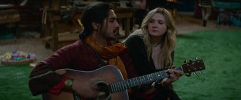 Movie still from “Zombieland: Double Tap” (2019), directed by Ruben Fleischer – A man and a woman are playing a guitar together; Medium shot, Over the shoulder angle