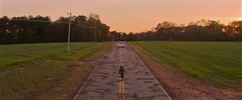 Movie still from “Zombieland: Double Tap” (2019), directed by Ruben Fleischer – A person riding a motorcycle down a wet road; Extreme Wide shot, High angle