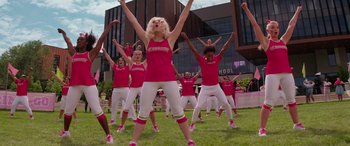 Movie still from “Zombies 3” (2022), directed by Paul Hoen – A group of people in pink shirts and white pants doing a dance move; Wide shot, Low angle