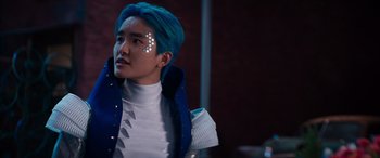 Movie still from “Zombies 3” (2022), directed by Paul Hoen – A man with blue hair and a white shirt is looking to his left; Close Up shot, Over the shoulder angle