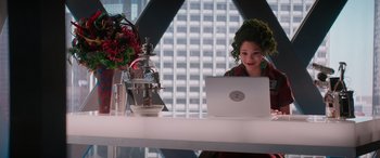 Movie still from “Zombies 3” (2022), directed by Paul Hoen – A woman sitting in front of a laptop computer on top of a table; Medium shot, Over the shoulder angle