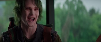 Movie still from “Zombies 3” (2022), directed by Paul Hoen – A man with green hair and a green backpack is smiling; Close Up shot, Over the shoulder angle