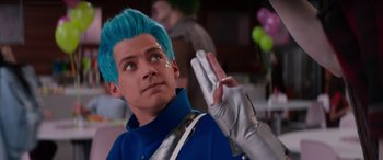 Movie still from “Zombies 3” (2022), directed by Paul Hoen – A man with blue hair and silver gloves is waving; Close Up shot, Over the shoulder angle