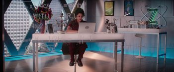 Movie still from “Zombies 3” (2022), directed by Paul Hoen – A woman sitting at a table using a laptop computer; Wide shot, Low angle
