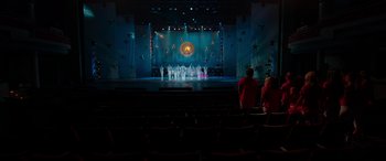 Movie still from “Zombies 3” (2022), directed by Paul Hoen – People are standing in front of a stage with lights; Extreme Wide shot, High angle