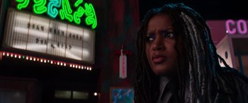 Movie still from “Zombies 3” (2022), directed by Paul Hoen – A woman with dreadlocks standing in front of a neon sign; Close Up shot, Over the shoulder angle