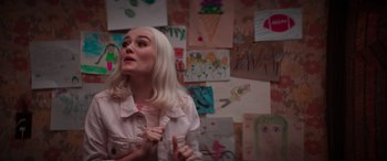 Movie still from “Zombies 3” (2022), directed by Paul Hoen – A woman with white hair standing in front of a bunch of drawings; Medium shot, Over the shoulder angle