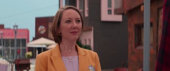 Movie still from “Zombies 3” (2022), directed by Paul Hoen – A woman in a yellow jacket standing in front of a building; Close Up shot, Over the shoulder angle