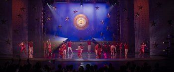 Movie still from “Zombies 3” (2022), directed by Paul Hoen – A group of people on a stage performing a dance; Extreme Wide shot, High angle