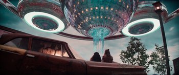 Movie still from “Zombies 3” (2022), directed by Paul Hoen – Two people sitting under a large metal structure; Extreme Wide shot, Low angle