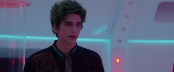 Movie still from “Zombies 3” (2022), directed by Paul Hoen – A young man with green hair is standing in front of a neon light; Close Up shot, Over the shoulder angle