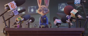 Movie still from “Zootopia” (2016), directed by Jared Bush – A rabbit character sitting in front of microphones; Medium shot, Over the shoulder angle
