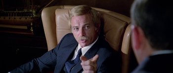 Movie still from “1990: The Bronx Warriors” (1982), directed by Enzo G. Castellari – A man in a suit sitting in a leather chair; Close Up shot, Low angle