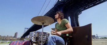 Movie still from “1990: The Bronx Warriors” (1982), directed by Enzo G. Castellari – A man sitting on a chair playing a drum set; Medium shot, Low angle