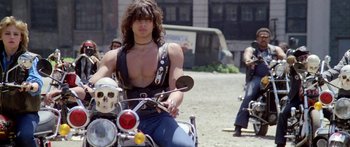 Movie still from “1990: The Bronx Warriors” (1982), directed by Enzo G. Castellari – A man riding a motorcycle on a dirt road; Medium shot, Low angle