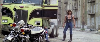 Movie still from “1990: The Bronx Warriors” (1982), directed by Enzo G. Castellari – A man standing in front of a large truck; Wide shot, Low angle