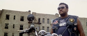Movie still from “1990: The Bronx Warriors” (1982), directed by Enzo G. Castellari – A man on a motorcycle in front of a brick building; Medium shot, Low angle