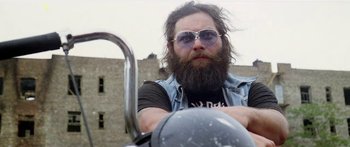 Movie still from “1990: The Bronx Warriors” (1982), directed by Enzo G. Castellari – A man with a beard and sunglasses on a motorcycle; Close Up shot, Low angle