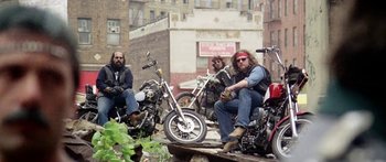 Movie still from “1990: The Bronx Warriors” (1982), directed by Enzo G. Castellari – A group of men sitting on motorcycles on a dirt road; Wide shot, Low angle