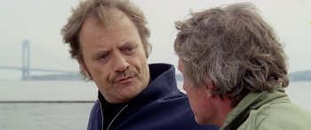 Movie still from “1990: The Bronx Warriors” (1982), directed by Enzo G. Castellari – A man with a beard is talking to another man; Close Up shot, Over the shoulder angle