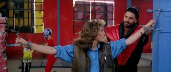 Movie still from “1990: The Bronx Warriors” (1982), directed by Enzo G. Castellari – A woman in a blue shirt and a brown leather vest; Medium shot, Low angle