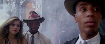 Movie still from “1990: The Bronx Warriors” (1982), directed by Enzo G. Castellari – A man in a suit and a hat standing next to another man in a suit; Close Up shot, Over the shoulder angle