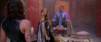 Movie still from “1990: The Bronx Warriors” (1982), directed by Enzo G. Castellari – A woman standing next to a man holding a sword; Wide shot, High angle