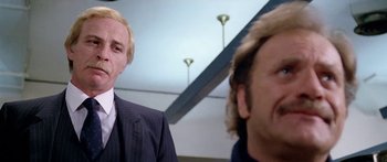 Movie still from “1990: The Bronx Warriors” (1982), directed by Enzo G. Castellari – A man in a suit and tie standing next to another man in a suit and tie; Close Up shot, Low angle