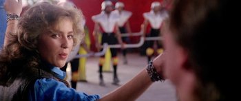 Movie still from “1990: The Bronx Warriors” (1982), directed by Enzo G. Castellari – A woman pointing at a group of people in a field; Close Up shot, Over the shoulder angle