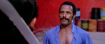 Movie still from “1990: The Bronx Warriors” (1982), directed by Enzo G. Castellari – A man in a blue shirt is talking to another man; Close Up shot, Low angle
