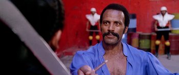 Movie still from “1990: The Bronx Warriors” (1982), directed by Enzo G. Castellari – A man with a mustache holding a paintbrush in front of another man; Close Up shot, Low angle