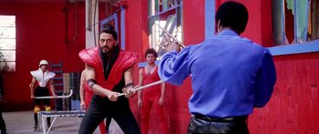 Movie still from “1990: The Bronx Warriors” (1982), directed by Enzo G. Castellari – Two men in red and one in black are practicing martial arts; Medium shot, Over the shoulder angle