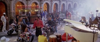 Movie still from “1990: The Bronx Warriors” (1982), directed by Enzo G. Castellari – A group of people standing around motorcycles in a room; Wide shot, High angle