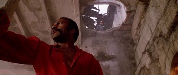 Movie still from “1990: The Bronx Warriors” (1982), directed by Enzo G. Castellari – A man in a red shirt standing in an abandoned building; Medium shot, Low angle