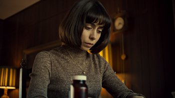 Movie still from “Fargo” (2014), created by Noah Hawley – A woman sitting in front of a table with a jar; Close Up shot, Low angle