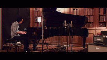 Movie still from “20,000 Days on Earth” (2014), directed by Iain Forsyth – A person standing in front of a piano in a room; Wide shot, High angle