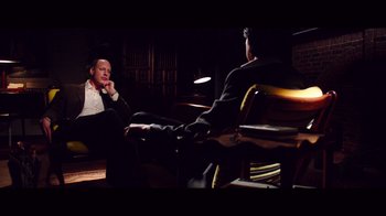 Movie still from “20,000 Days on Earth” (2014), directed by Iain Forsyth – A man sitting on a chair talking to another man in a black suit; Medium shot, Over the shoulder angle